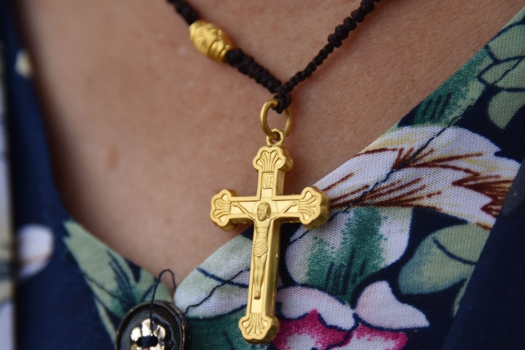 A worshipper wears a cross outside a Catholic church in Puyang, in China's central Henan province. Photo by AFP
