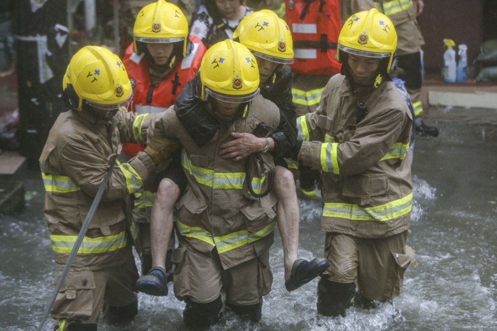 Firefighters help residents escape flooding in Lei Yue Mun, east Kowloon. Photo: Winson Wong