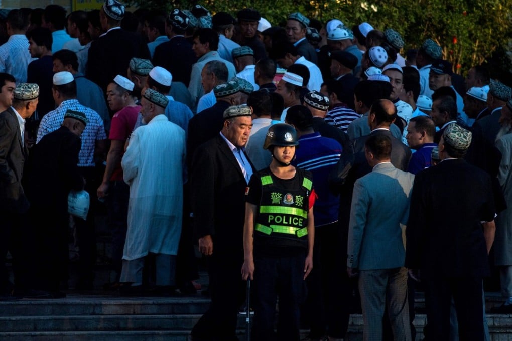 A policeman stands guard as the faithful arrive for morning prayers during Eid ul-Fitr, at a mosque in the city of Kashgar in Xinjiang in June 2017. Photo: AFP