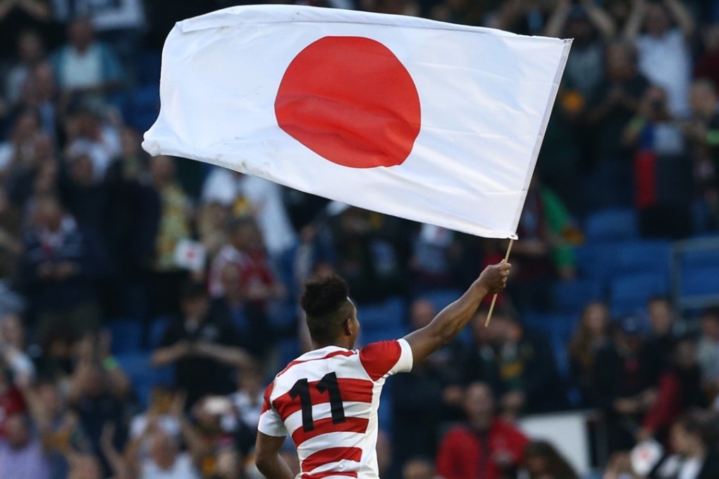 Japan wing Kotaro Matsushima waves the national flag as the team celebrate beating South Africa at the 2015 World Cup in England. Photo: AFP