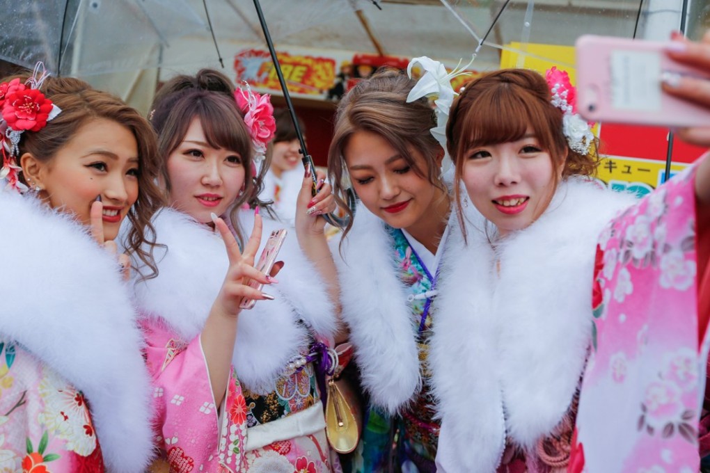 Young Japanese women take a wefie on Coming of Age Day. Female adults have a rough time in Japan. They are paid a third less than men for similar work. Photo: EPA