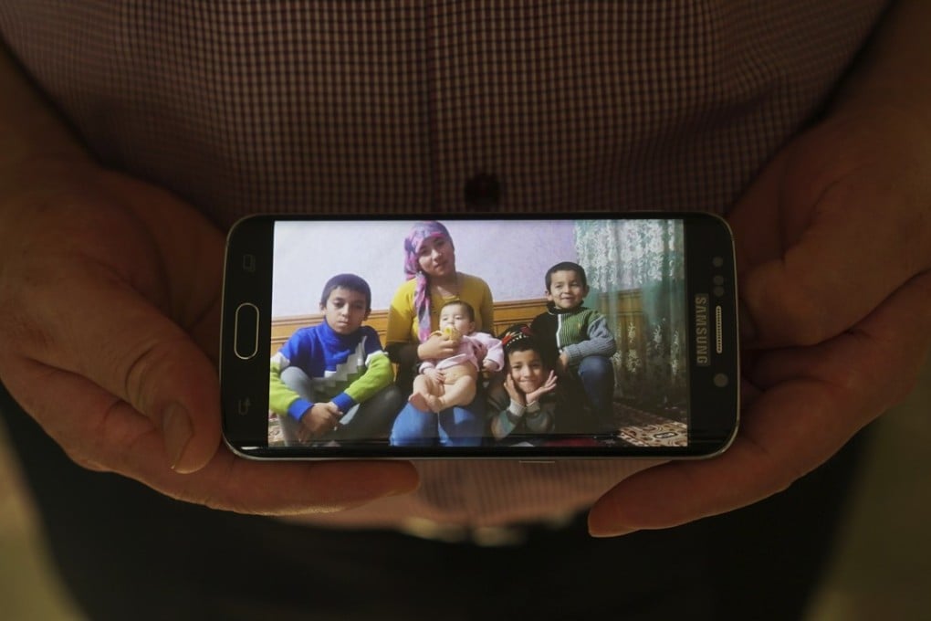 In this August 23 photo, Adil, 42, father to five children and a businessman from Kashgar, China, holds a phone showing an image of the family he left behind in China. Adil got stuck in Turkey during a business trip after hearing that the Chinese government was seizing passports, and hasn't seen his children since. Three of his children were ordered to attend newly-built boarding schools in Kashgar and Turpan before he got stuck in Turkey. Photo: AP