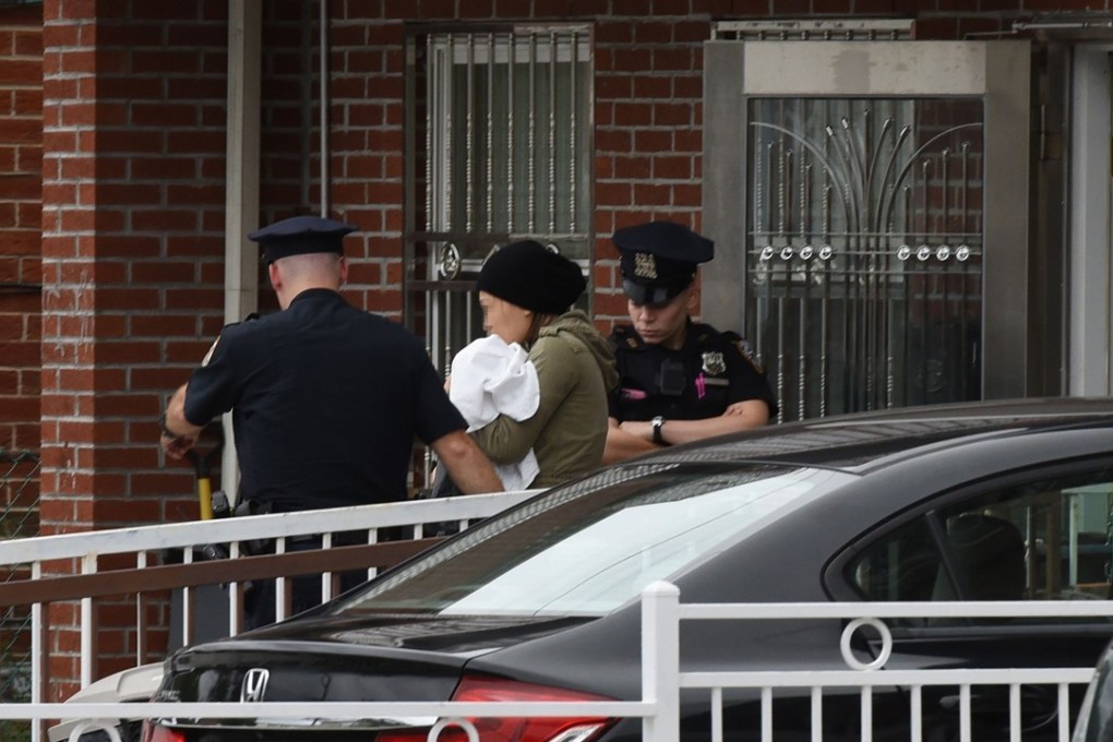 An unidentified woman is escorted by police out of a day care centre, Mei Xin Care Incorporated, located at a home in the Flushing area of Queens, New York, on September 21, 2018, after a female attacker stabbed five people, including three infants. Photo: AFP. Edit: SCMP