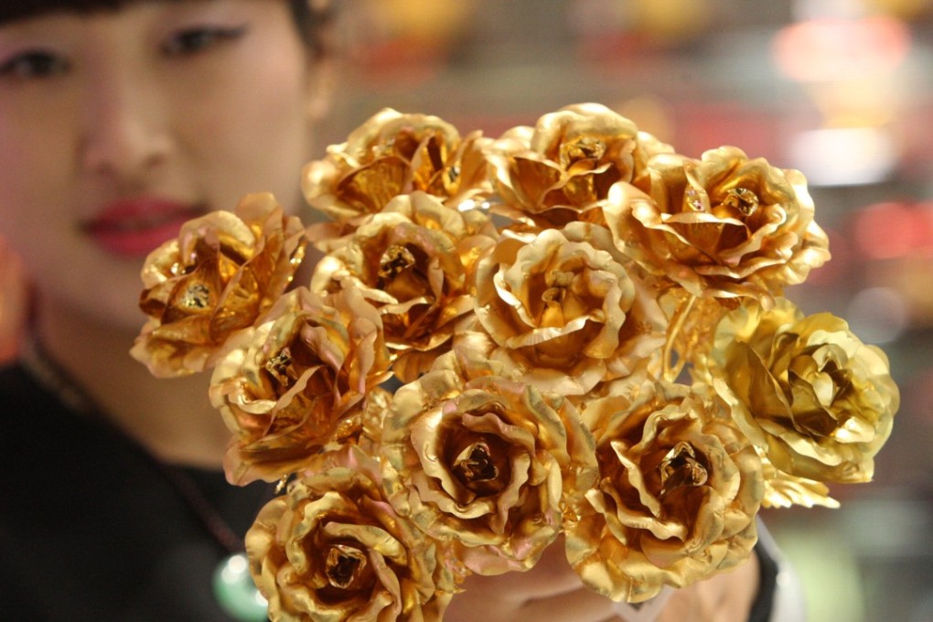 A worker shows off gold foil roses, a popular Valentine’s Day gift, at a shop in Yantai, in east China’s Shandong province, in February 2016. Chinese consumers tend to have a high appetite for the noble metal. Photo: Xinhua