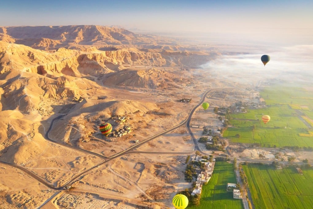 A hot air balloon flights over the west bank of the Nile, landscape of mountains and green valley