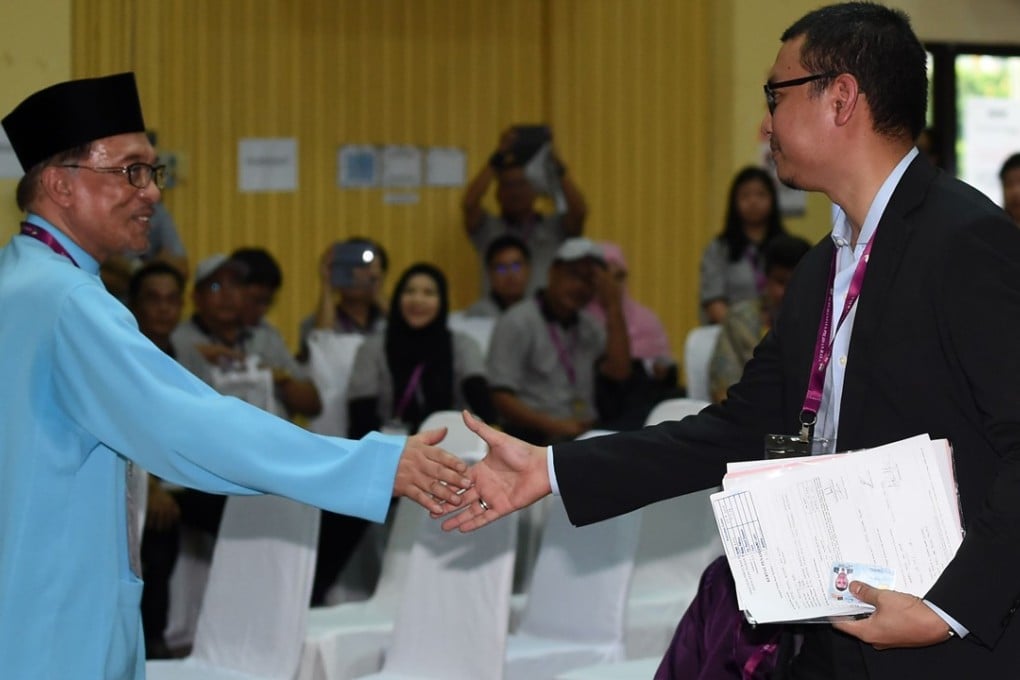 President of the People’s Justice Party and leader of the Pakatan Harapan coalition Anwar Ibrahim (left) shakes hands with independent candidate Saiful Bukhari Azlan after submitting his documents at the nomination centre for a by-election in Port Dickson on September 29, 2018. Photo: AFP