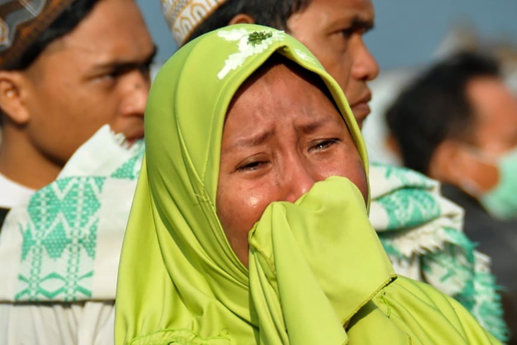 A woman cries as people look at the damage in Palu. Photo: AFP