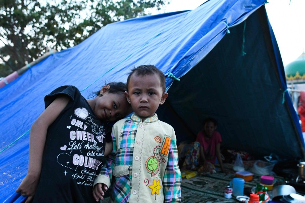 Children pose in front of a tent in Palu, Indonesia, where they took refuge after an earthquake and tsunami hit the area on September 28. Photo: AFP