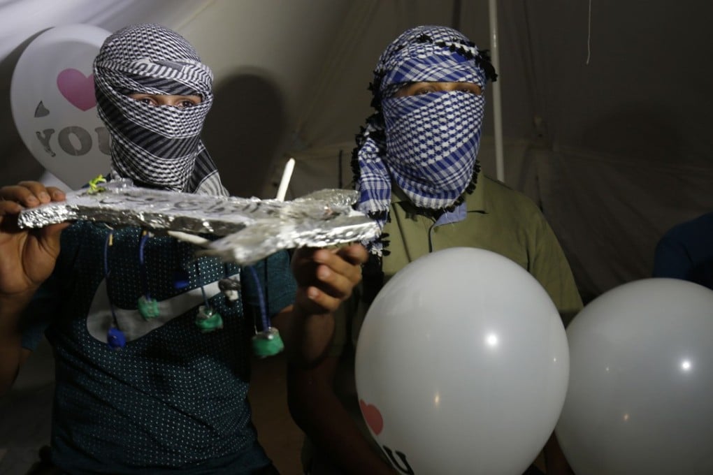 Masked Palestinian protesters calling themselves the ‘night confusion units’ hold incendiary devices attached to balloons to be flown towards Israel. Photo: AFP