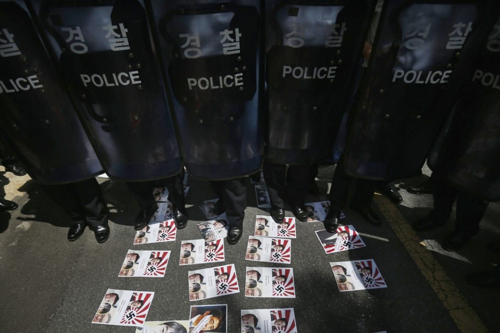 South Korean police at an anti-Japan protest. On the ground are leaflets featuring the Rising Sun flag, which is seen by many in Asia as a symbol of Japan’s colonial period. Photo: Reuters