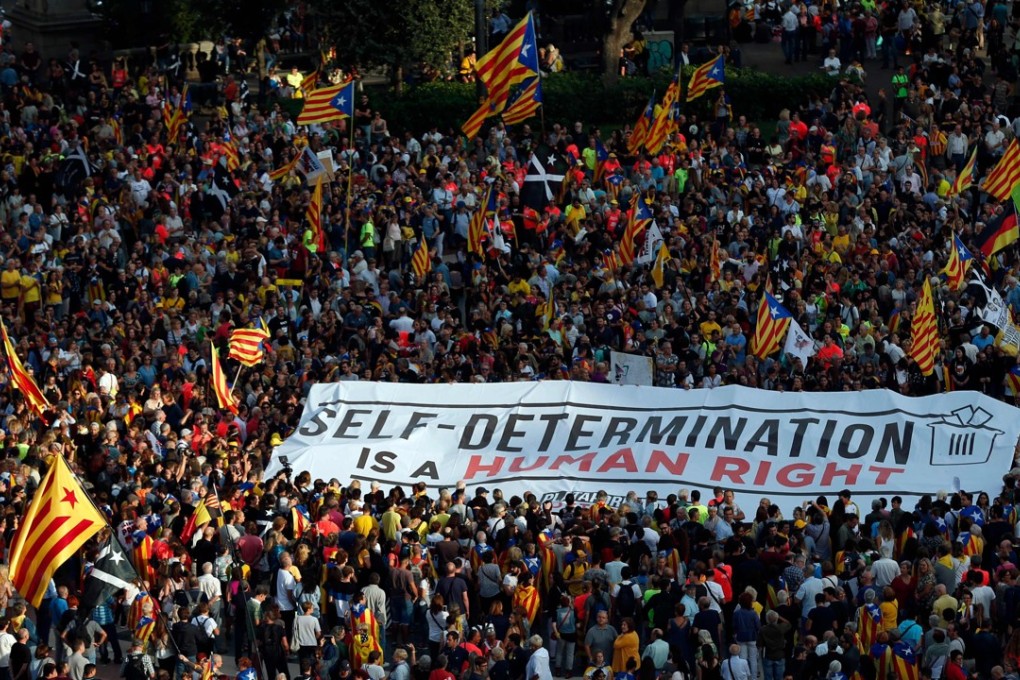 People unfold a banner demanding self-determination during a demonstration in Barcelona on Monday to commemorate the first anniversary of a banned referendum on secession that was marred by police violence. Photo: AFP