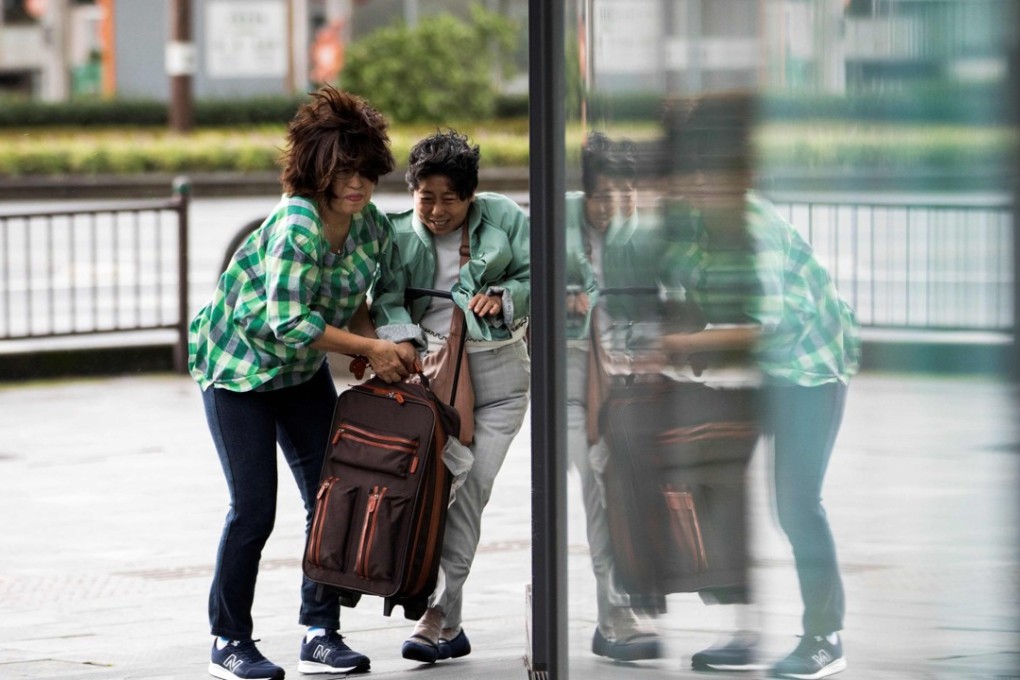 Pedestrians carry a bag as they walk against a strong wind after Typhoon Trami hit the city of Kagoshima on Kyushu island. The storm left four people dead, authorities said. Photo: AFP
