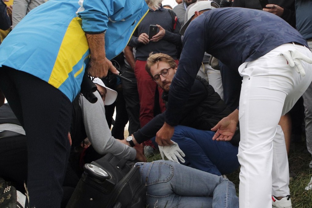 Brooks Koepka checks on a spectator he injured when his ball hit her on the sixth hole on the opening day of the Ryder Cup at Le Golf National. Photo: AP