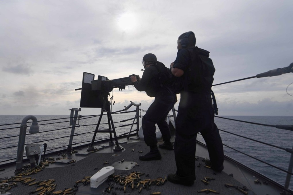 US Navy personnel fire a .50-cailber machine gun during a weapon’s qualification course aboard the USS Mustin in the South China Sea on July 5. Photo: US Navy Handout via Reuters