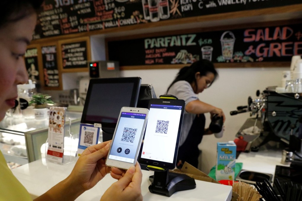 A Singaporean woman pays for her coffee at a cashless cafe. Photo: Reuters