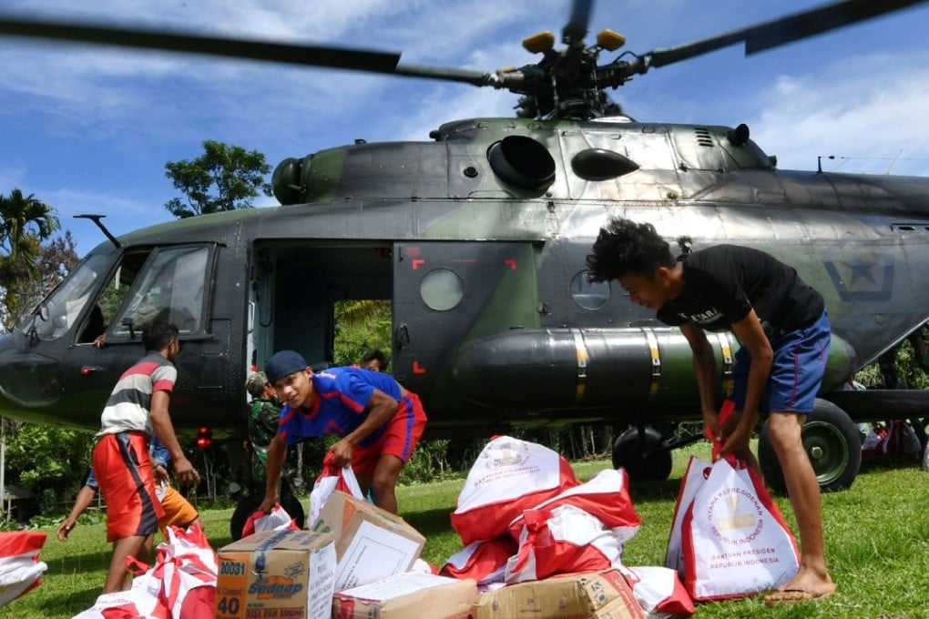 Indonesian villagers offload aid from a military helicopter in Proo village, Lindu district in Central Sulawesi's Sigi regency. Photo: AFP