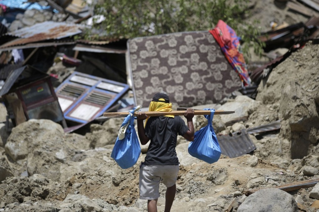 A man carries belongings from his toppled house in the Balarola neighbourhood of Palu city. Photo: AP
