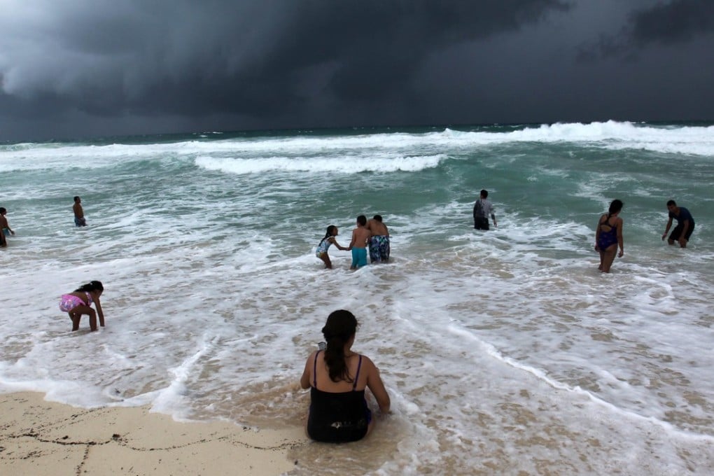 People swim in the turbulent sea at a beach in Cancun, Quintana Roo, Mexico, on Sunday, as the depression that would become Hurricane Michael passes by. Photo: EPA-EFE