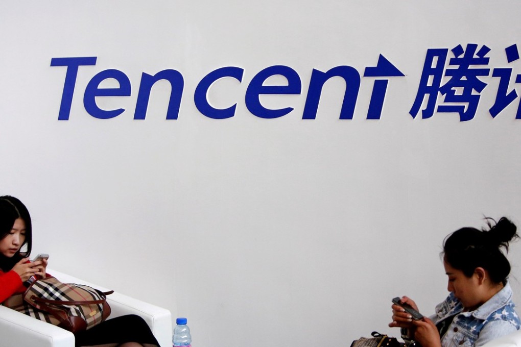 Visitors use their smartphones underneath the logo of Tencent at the Global Mobile Internet Conference in Beijing. Photo: Reuters