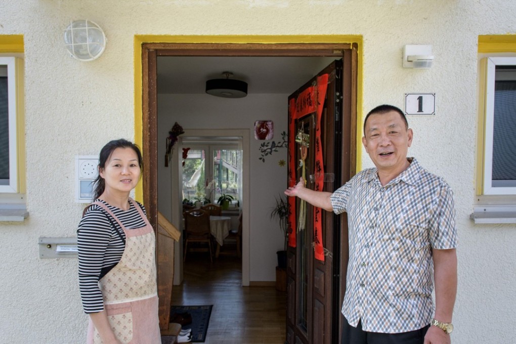 Zhang Jianxin and his wife Yang from China, pose in front of their house at the so-called ‘Oak Garden’ residential complex. Photo: AFP