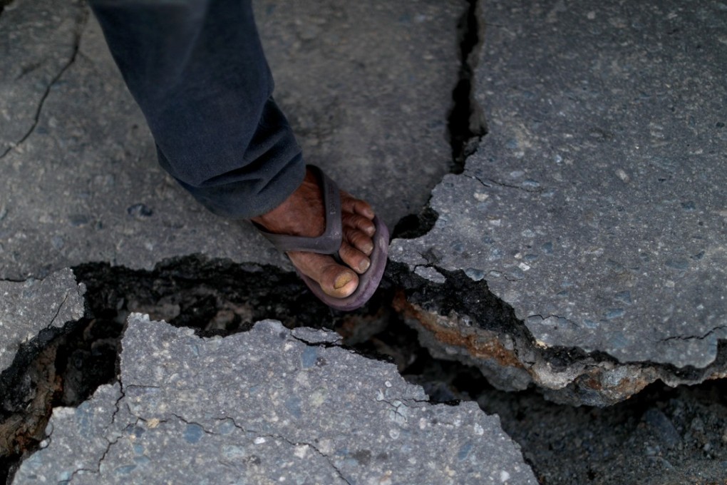 A man steps on a crack in a road at Balaroa neighbourhood hit by the earthquake and liquefaction in Palu, Central Sulawesi, Indonesia, on Wednesday. The country was struck by a second earthquake on Wedneday. Photo: Reuters