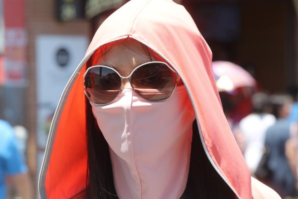 A woman covers up to protect herself from the sun in Tsim Sha Tsui, Hong Kong. Photo: K.Y. Cheng