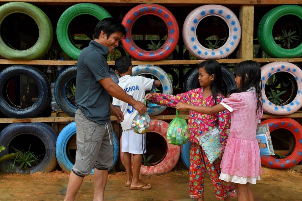 Ouk Vandey receives salvaged plastic water bottle caps from students as a fee for studying. Photo: AFP