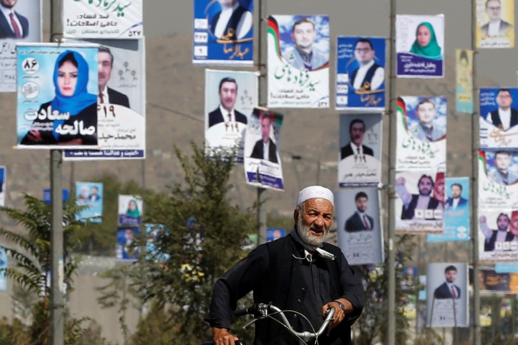 A man walks with his bicycle in front of election posters of parliamentary candidates during the first day of election campaign in Kabul, Afghanistan. Photo: Reuters