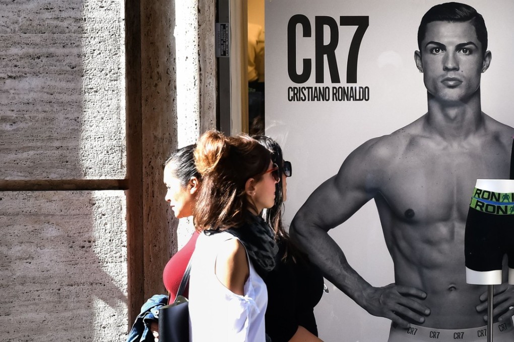 Passersby walk past an advertising poster for an underwear brand, showing a picture of Juventus’ Portuguese forward Cristiano Ronaldo in a shop window. Photo: AFP