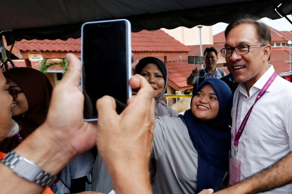 Anwar Ibrahim takes a photo with supporters as he visits a polling station. Photo: Reuters
