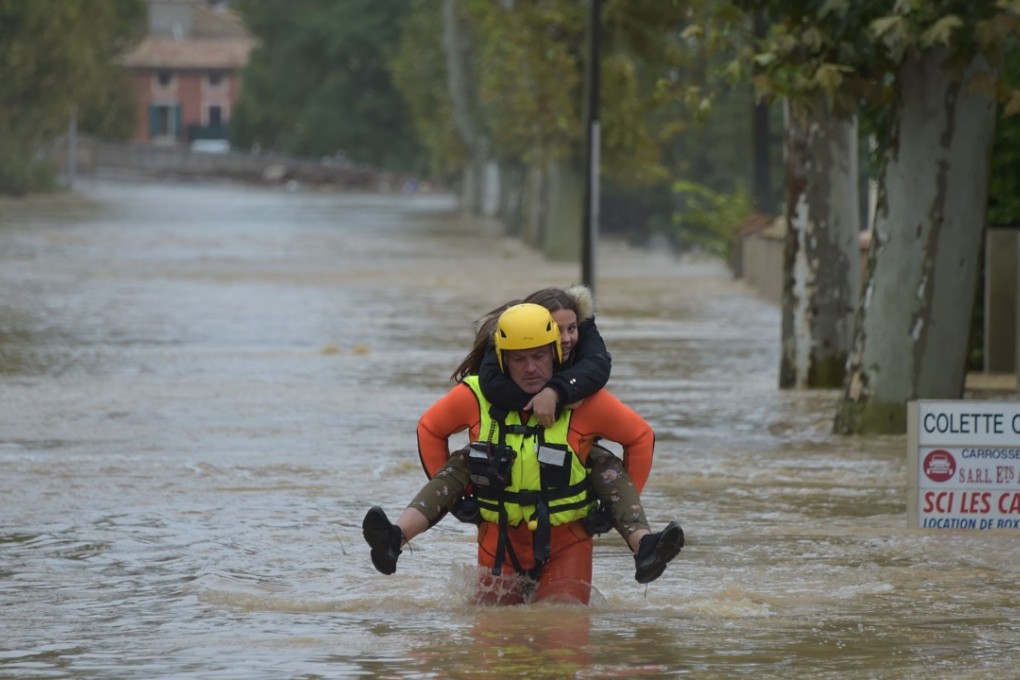A firefighter helps a youngster in a flooded street during rescue operation following heavy rains that saw rivers bursting banks on Monday in Trebes, near Carcassone, southern France. Photo: Agence France-Presse