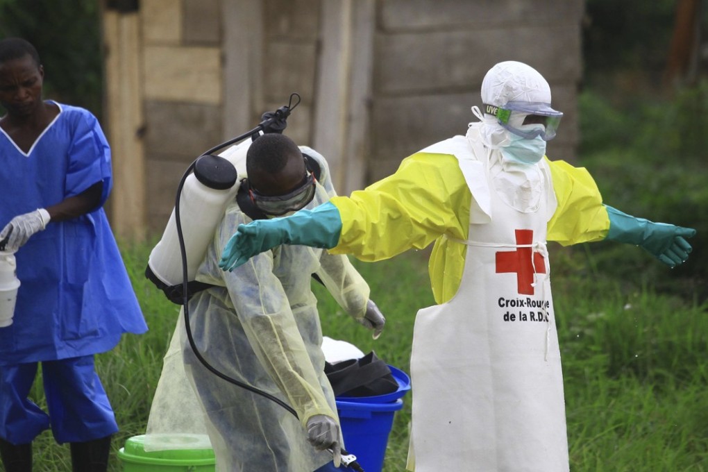 A health worker sprays disinfectant on his colleague after working at an Ebola treatment centre in Beni, Eastern Congo. Photo: AP