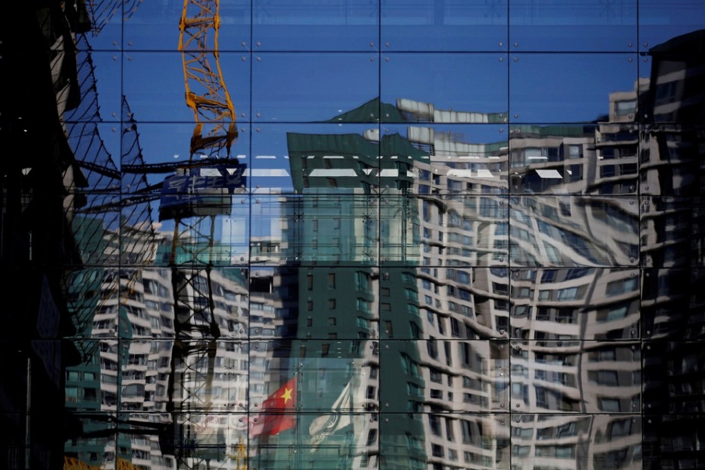 A construction site and residential building reflected on the glass wall of a building in Beijing. Photo: Reuters