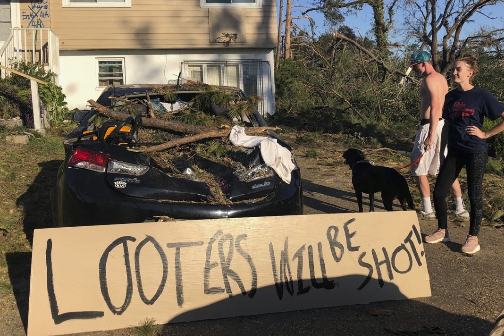 Shauna Benefield and Alex Edwards stand near a sign warning looters in front of their house in Marianna, Florida. Photo: AP