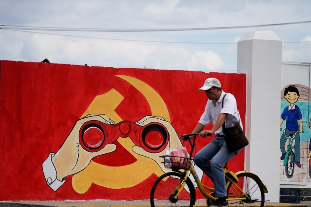 A man rides his bicycle next to a mural showing an emblem of the Communist Party of China along a street in Shanghai, China, 2018. Photo: Reuters