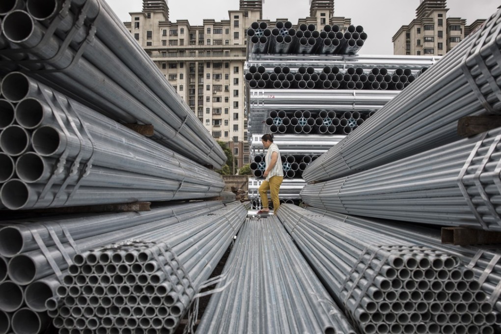 A worker walks over bundles of steel pipe stacked at a stockyard on the outskirts of Shanghai in this file photo. Photo: Bloomber