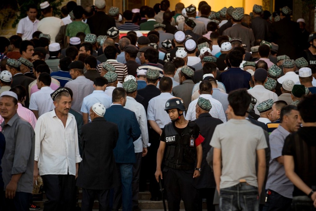 A policeman stands guard as Muslims arrive for the Eid ul-Fitr morning prayer at the Id Kah Mosque in Kashgar, Xinjiang, China. Beijing says the heavy police presence is needed to prevent the spread of Islamic extremism, but analysts warn that Xinjiang is becoming an open-air prison. Photo: AFP