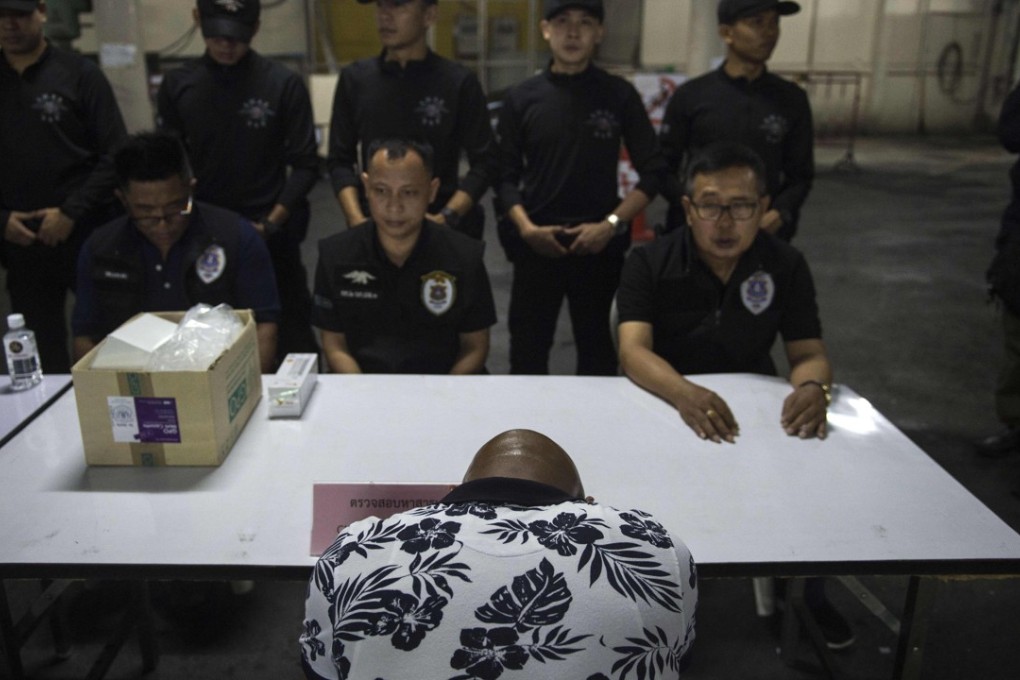 Police hold a foreigner for questioning in Bangkok's Nana district. Photo: AFP