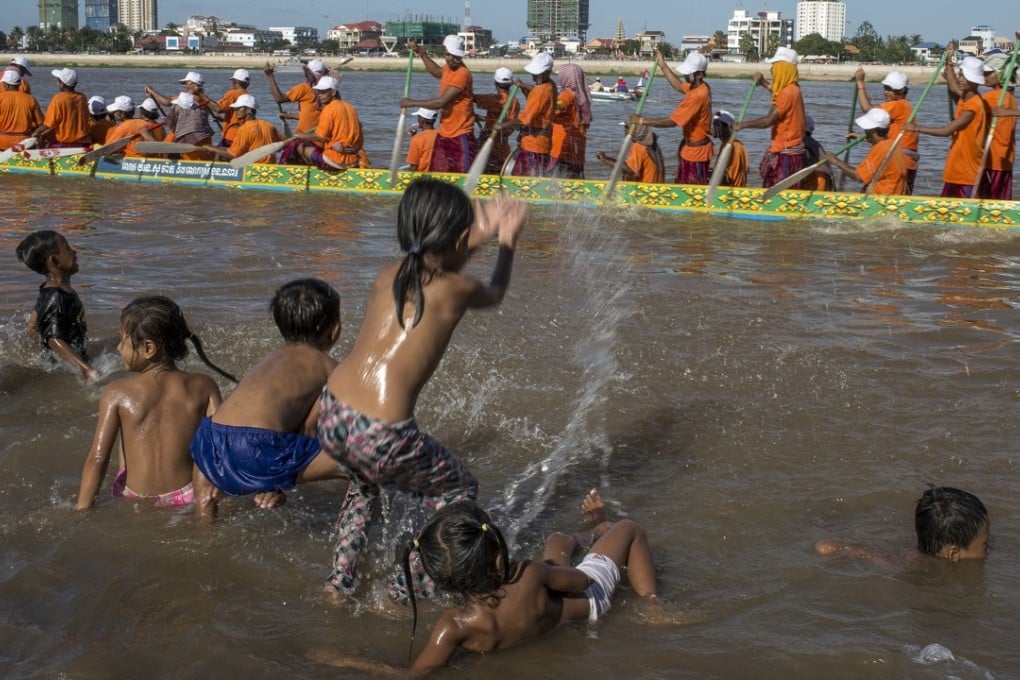 A group of children throw water at the crew of a racing boat as they pass by after finishing their race on the Tonle Sap river during the Water Festival in Phnom Penh, Cambodia. Photo: Omar Havana