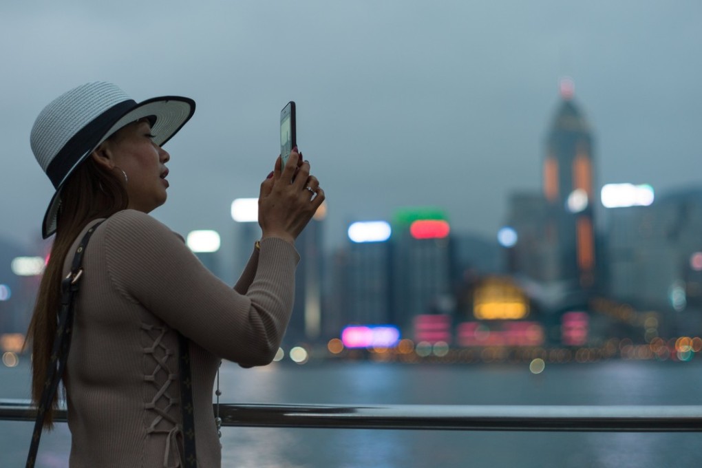 A tourist takes a picture of the view of Victoria Harbour waterfront at dusk in Hong Kong in March. The view of the Hong Kong Island skyline is one of the most popular, and free, tourist attractions in the city. Photo: EPA-EFE