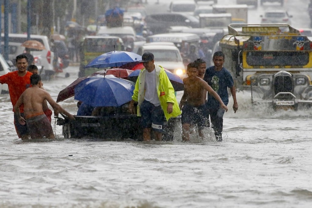 Volunteers ferry commuters through floodwaters following overnight monsoon rains brought by a tropical storm, in suburban Quezon City, northeast of Manila, in July. Photo: AP