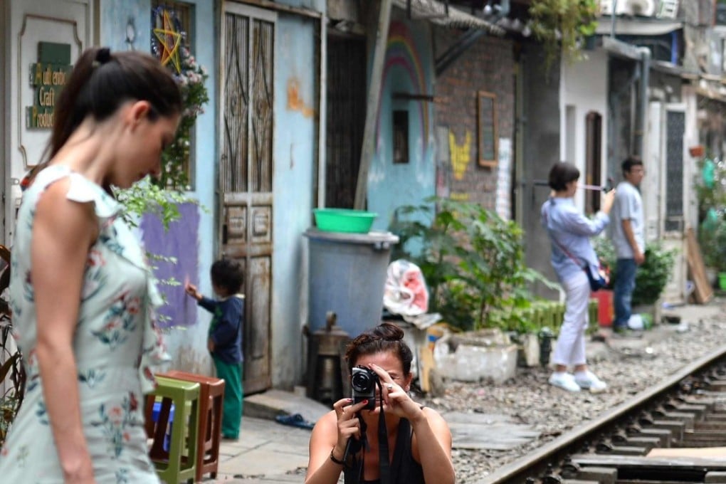 A tourist poses for a photo on a railway track passing through an old residential district in central Hanoi. Photo: AFP