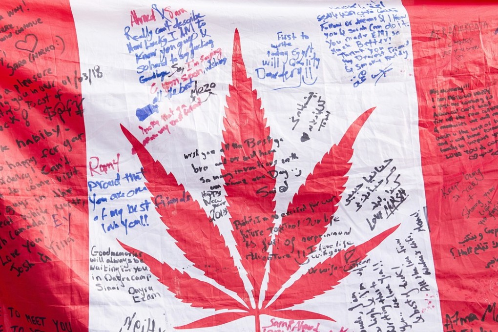 People hold up a Canadian flag with a marijuana logo on it outside a government cannabis store in Montreal. Photo: AP