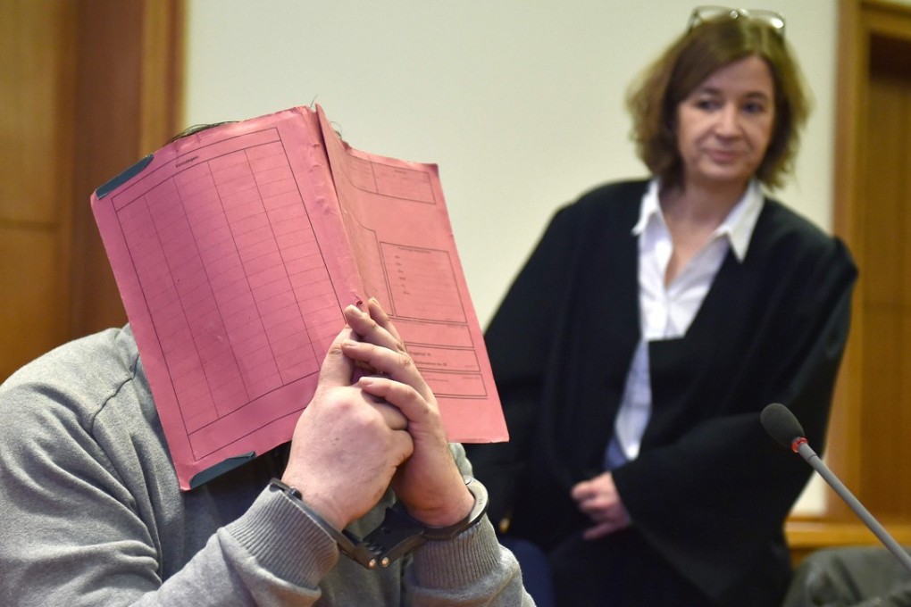 Niels Hoegel hides his face behind a folder as he waits next to his lawyer for the opening of an earlier trial. File photo: AFP