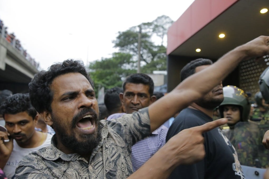 A supporter of newly appointed Sri Lankan prime minister Mahinda Rajapaksa shouts at police officers outside petroleum ministry building in Colombo. Photo: AP Photo