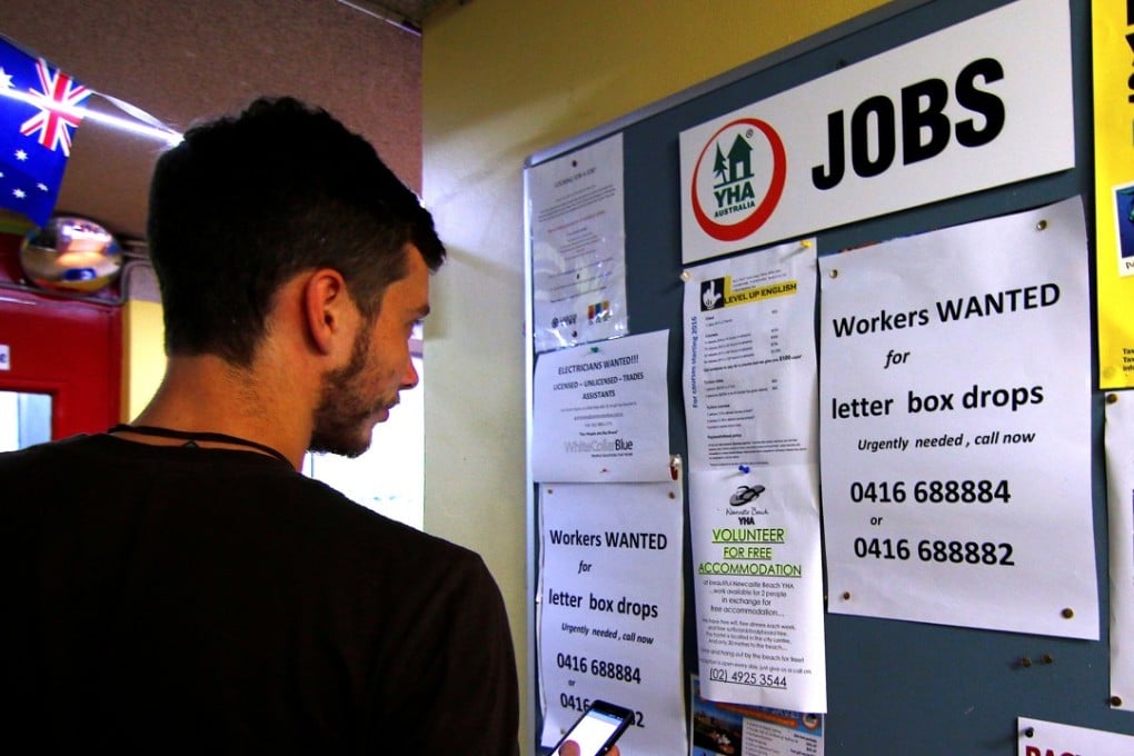 A man uses his phone to record a job add posted on a notice board at a backpacker hostel in Sydney, Australia. Photo: Reuters