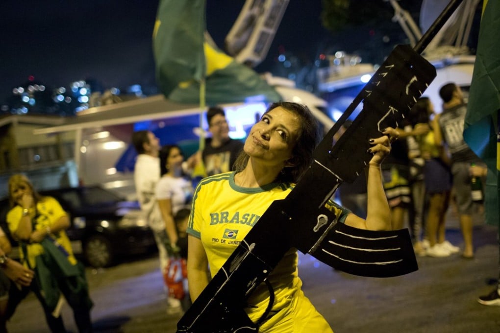 A supporter of presidential candidate Jair Bolsonaro, holds an oversized, fake rifle, as she celebrates the election results in Rio de Janeiro. Photo: AP