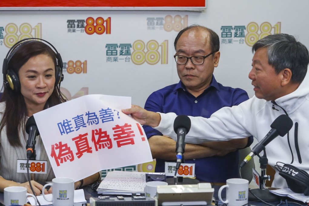 Labour Party veteran Lee Cheuk-yan (right) hands a banner reading “hypocrisy” to pro-establishment candidate Chan Hoi-yan as Frederick Fung Kin-kee, a pan-democrat running as an independent, looks on at a forum at Commercial Radio, in Kowloon Tong, on October 23. Photo: Edmond So