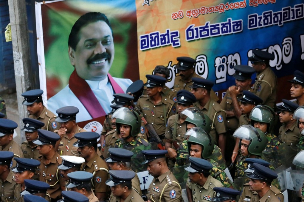 Members of Sri Lanka's Special Task Force and the police stand guard next to a poster of newly appointed Prime Minister Mahinda Rajapaksa after an official security guard of sacked minister Arjuna Ranatunga shot and wounded three people. Photo: Reuters