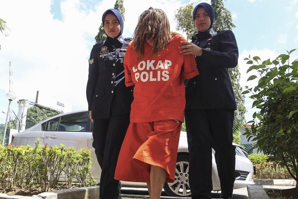 Samantha Williams is escorted by a Royal Malaysian Police officer as they arrive at Langkawi court on Tuesday. Photo: EPA